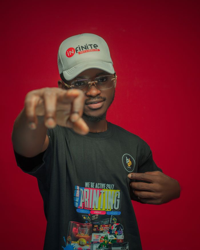services-03 Confident young man wearing a branded cap and t-shirt, pointing directly at the camera against a red background.