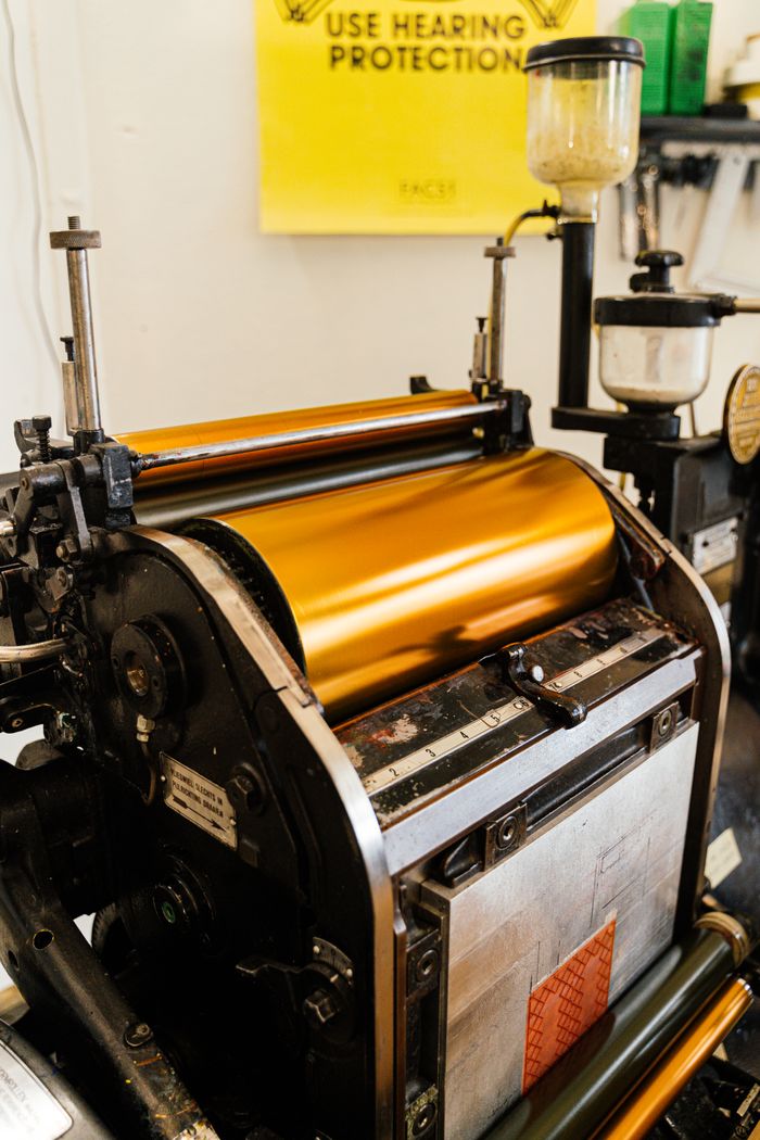 Close-up of a vintage printing press with golden metallic rollers, highlighting industrial design.