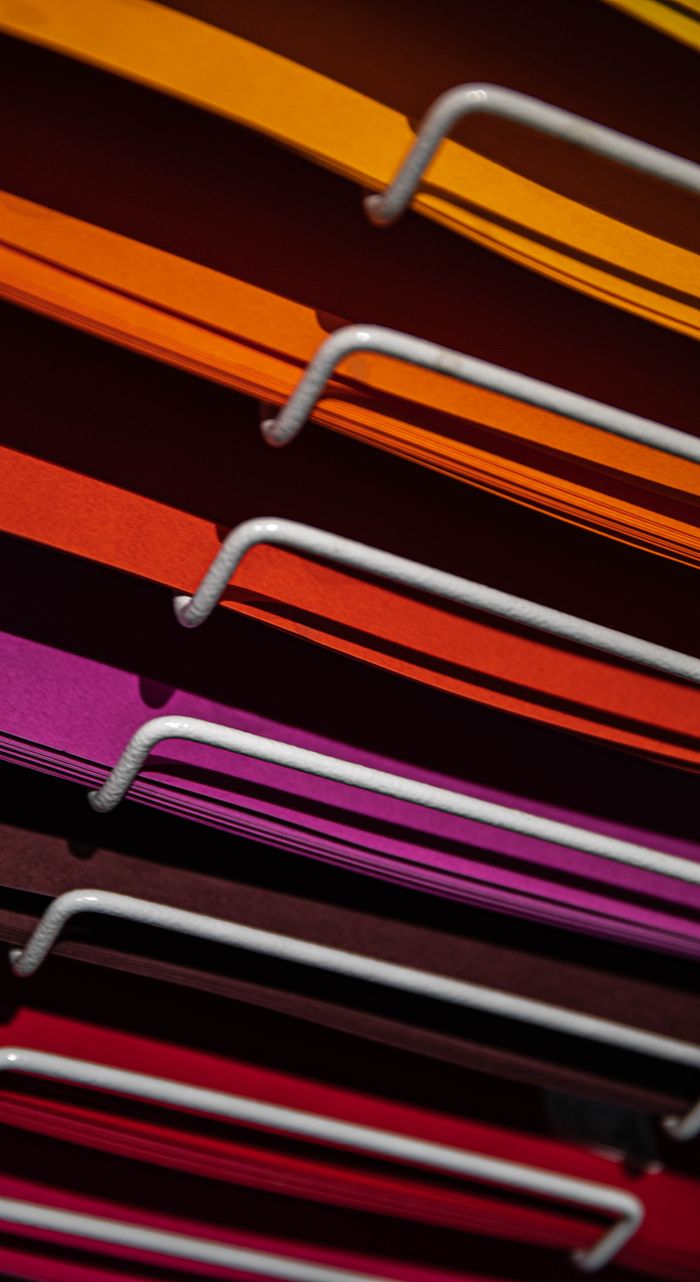 services-02 Close-up of stacked colored paper and metal bars with vibrant colors.
